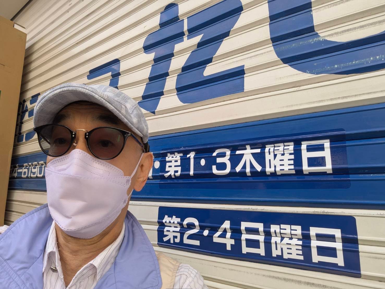 看板職人の田辺勝則。自身が書いたシャッターの営業日表示の前で