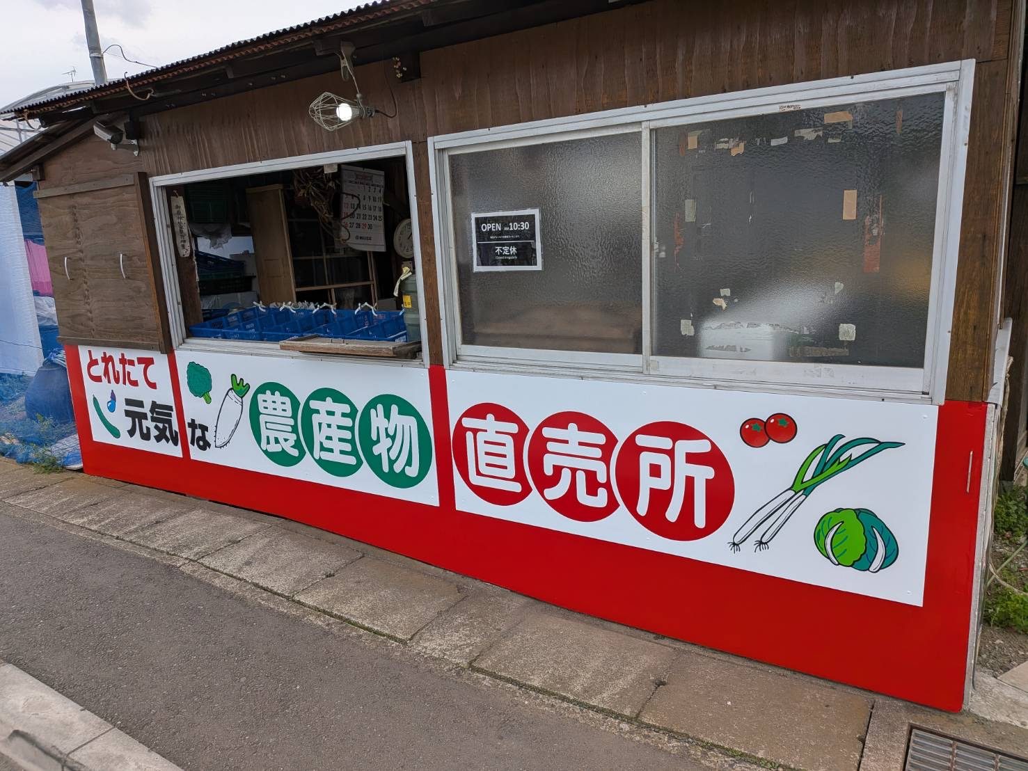 農産物直売所の店舗看板。赤と白の地に野菜の絵